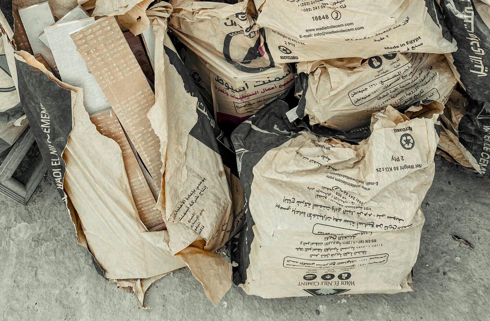 A pile of cement bags placed near a wooden fence, hinting at construction or renovation work.